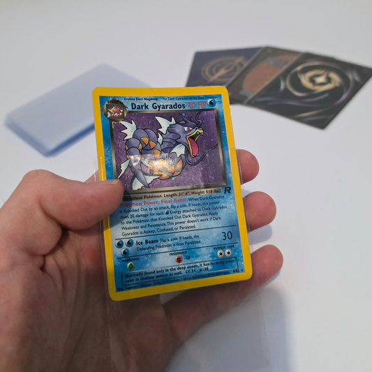 Clear penny sleeve protecting a Pokémon Dark Gyarados trading card during handling.